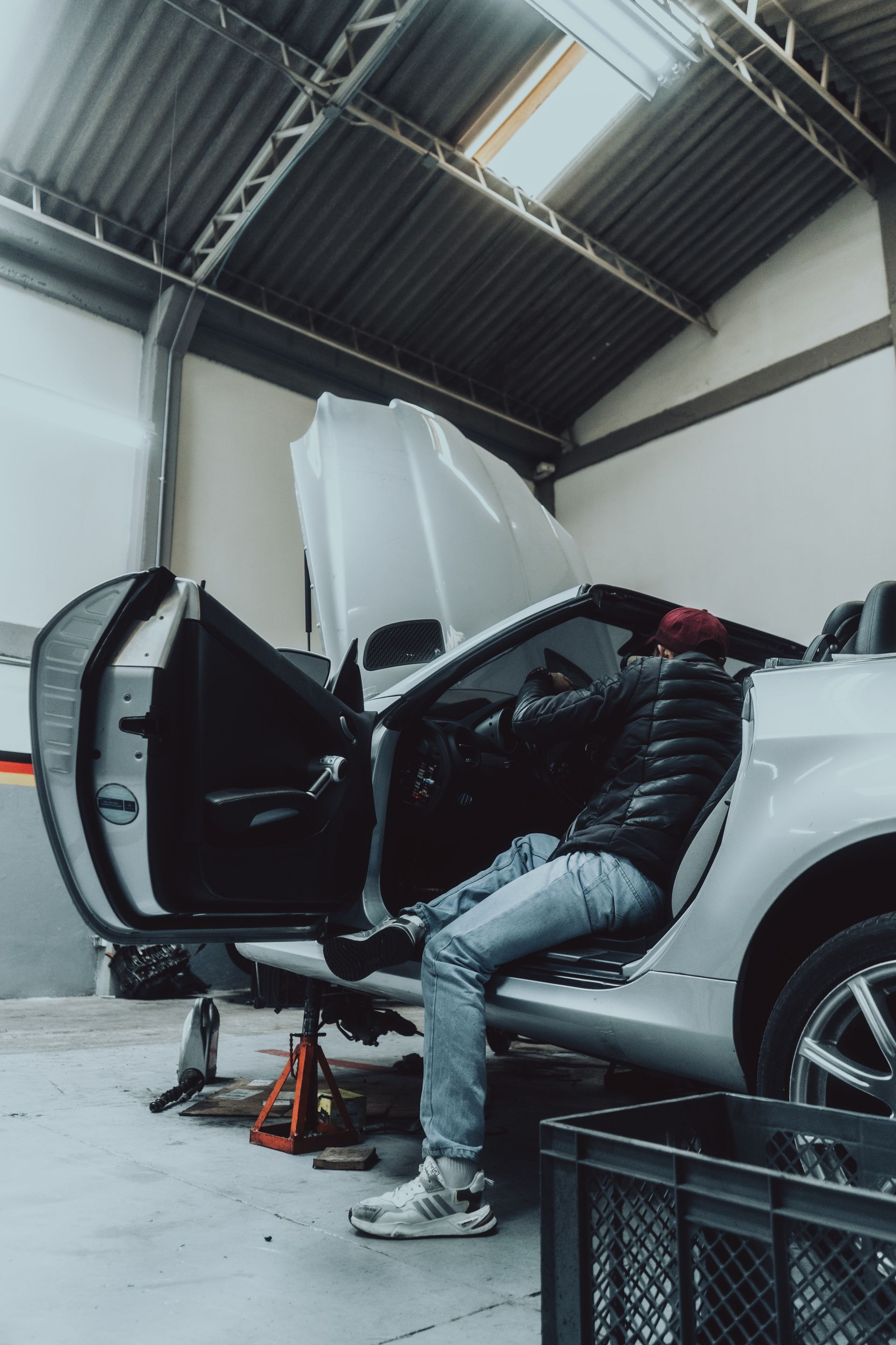 A man is sitting in the back seat of a car in a garage.