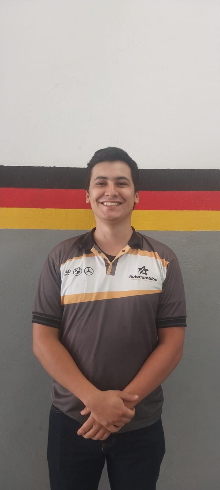 A young man is standing in front of a wall with a german flag painted on it.