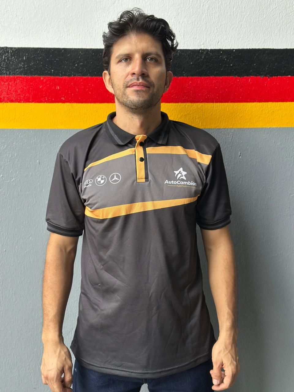 A man wearing a polo shirt stands in front of a german flag