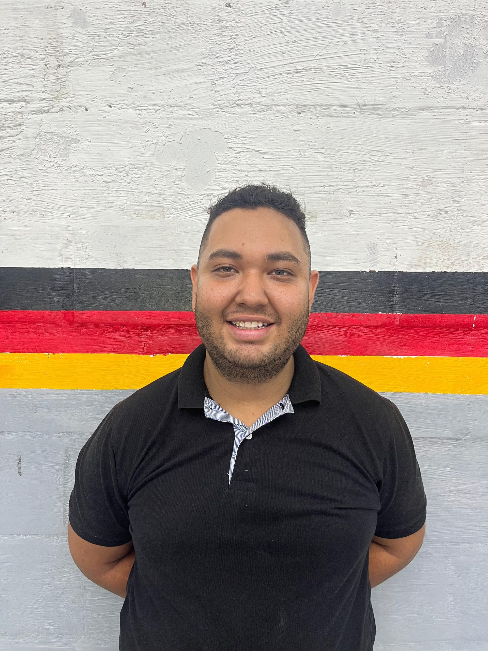 A man in a black and yellow shirt is standing in front of a german flag