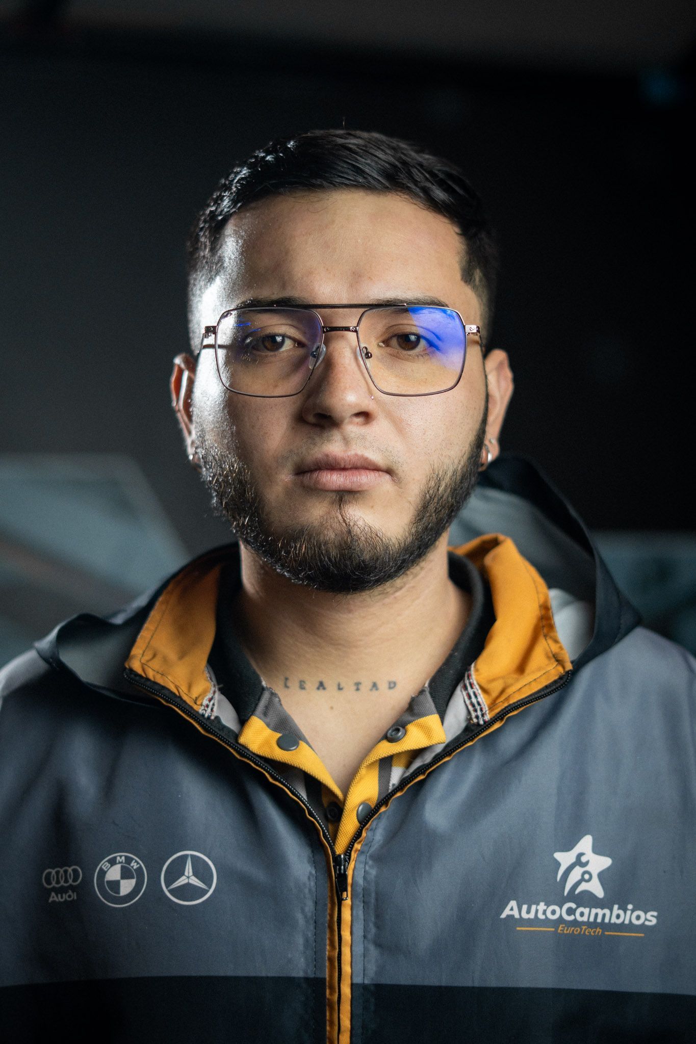 A man wearing glasses and a jacket that says autocambios