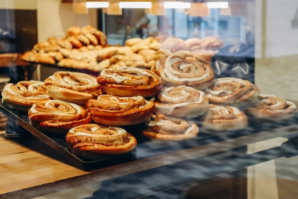 A display case filled with cinnamon rolls in a bakery.