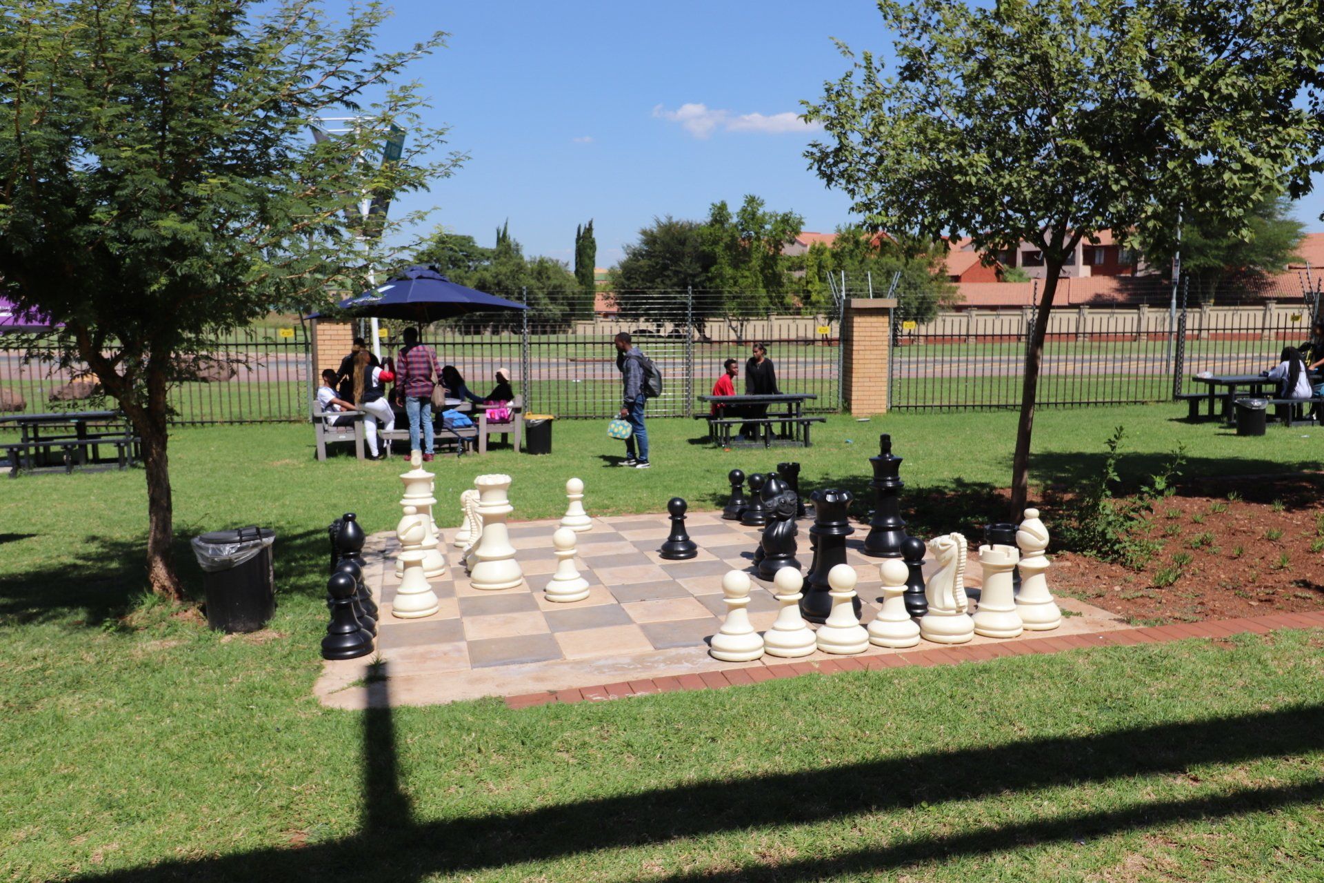 a large chess board in a park with people sitting at picnic tables