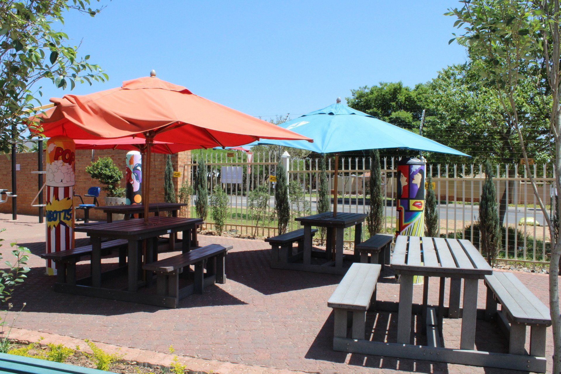 a picnic area with tables and umbrellas and a popcorn machine