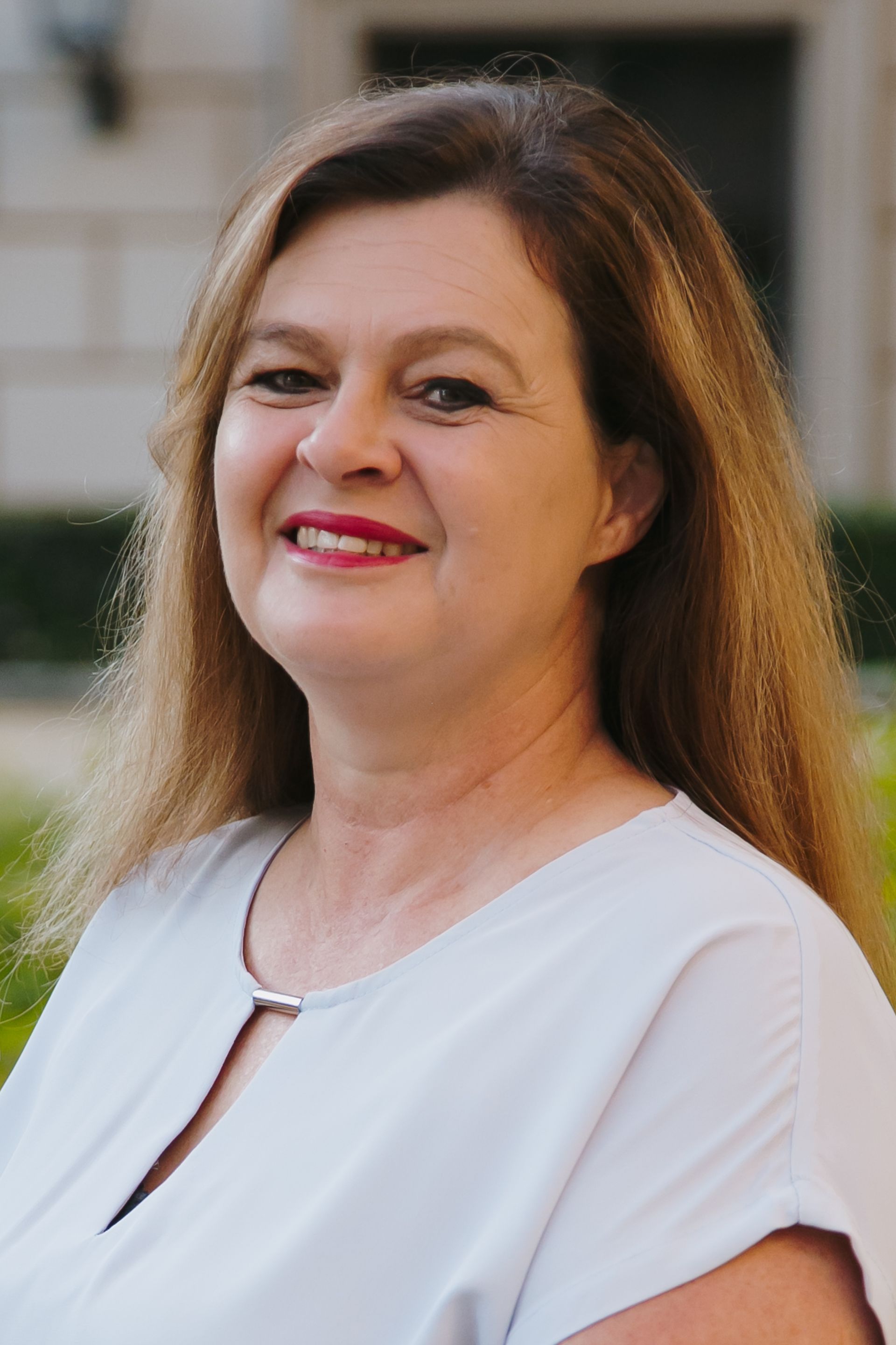 A woman in a white shirt is smiling for the camera.