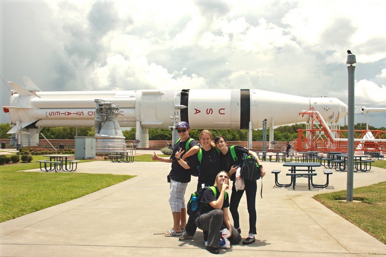 A group of people posing in front of a rocket that says USA