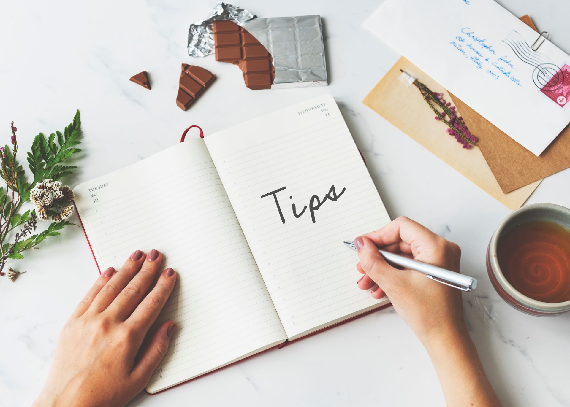 A person is writing tips in a notebook with a pen.