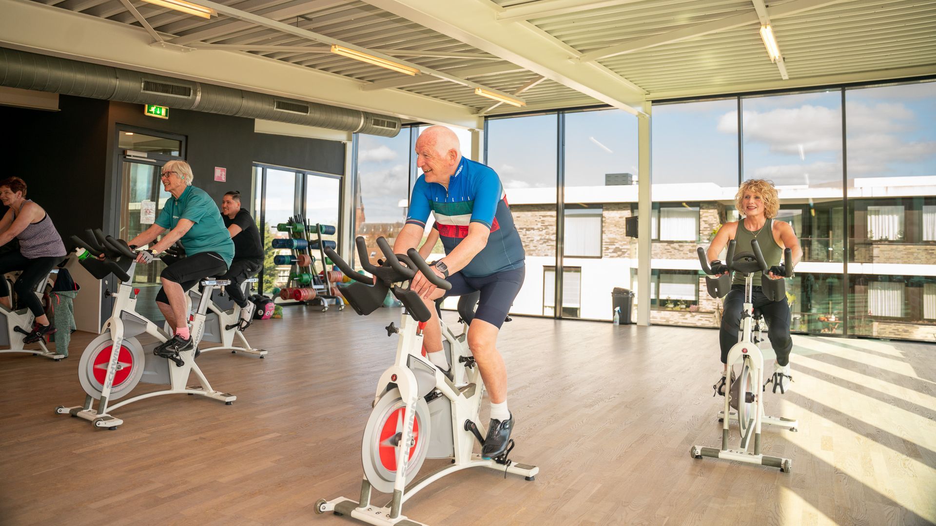 Een groep mensen fietst op een hometrainer in een sportschool.
