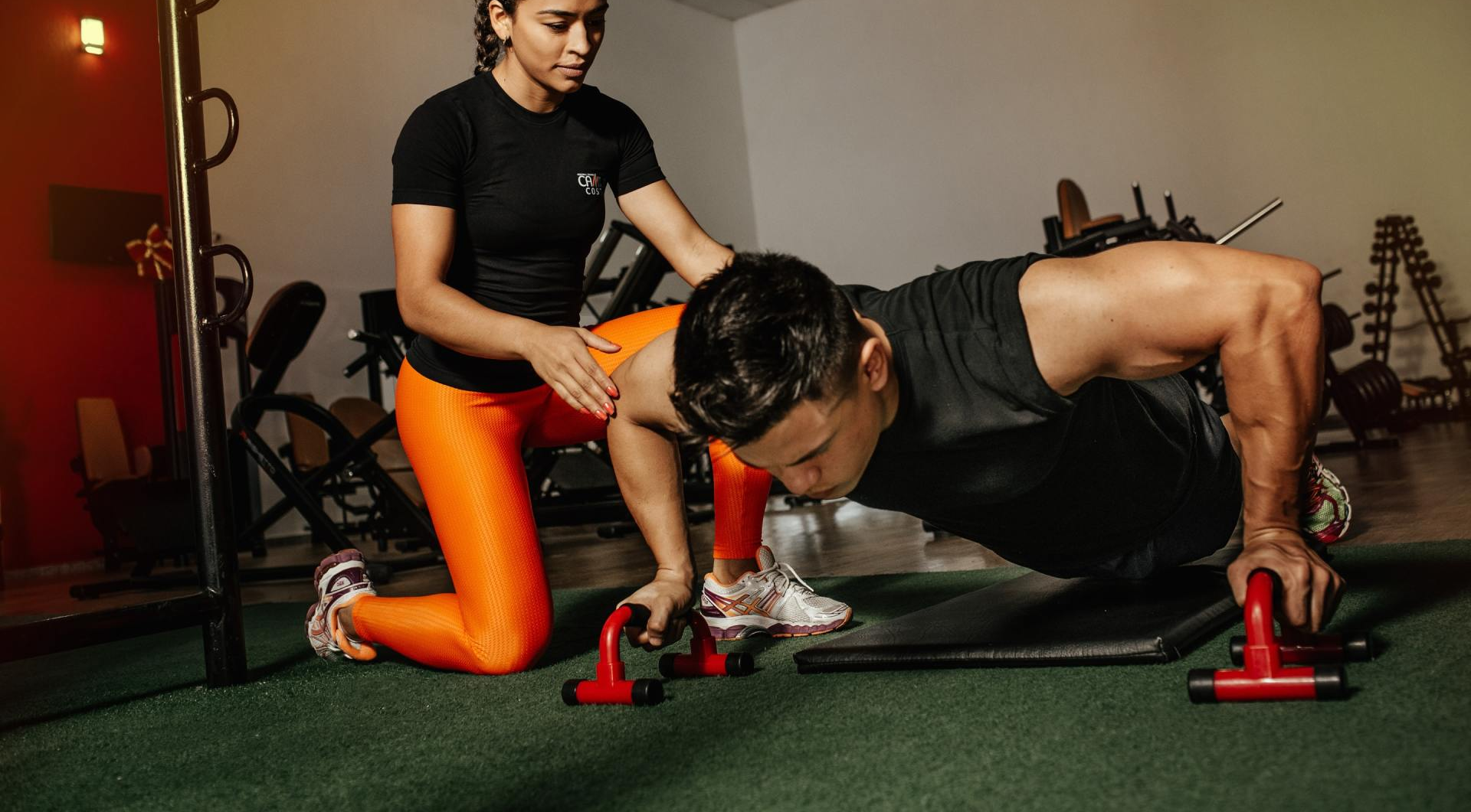 Een vrouw helpt een man met push-ups in de sportschool.