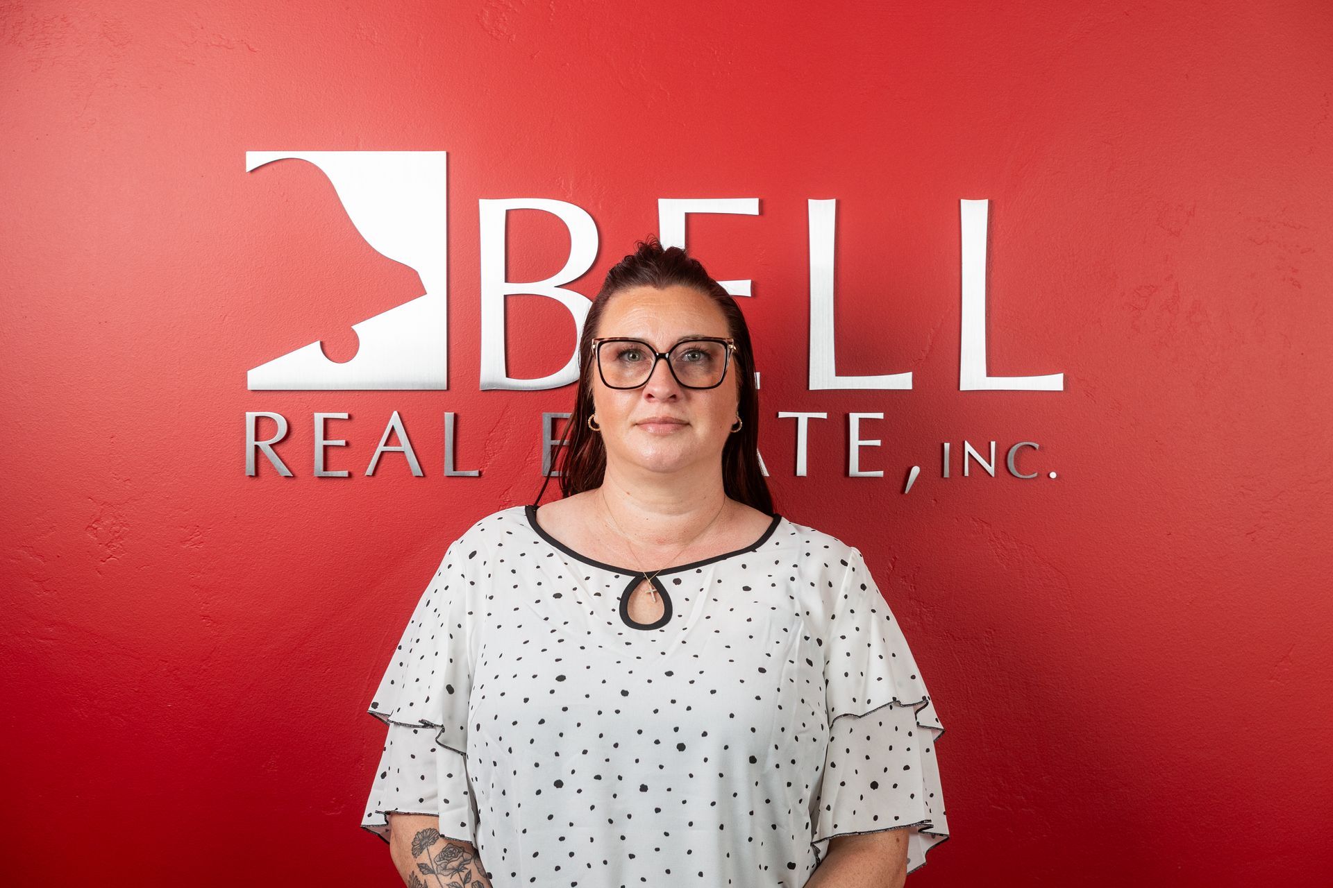 A woman is standing in front of a bell real estate sign.