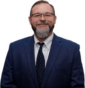 A man with a beard and glasses is wearing a blue suit and tie