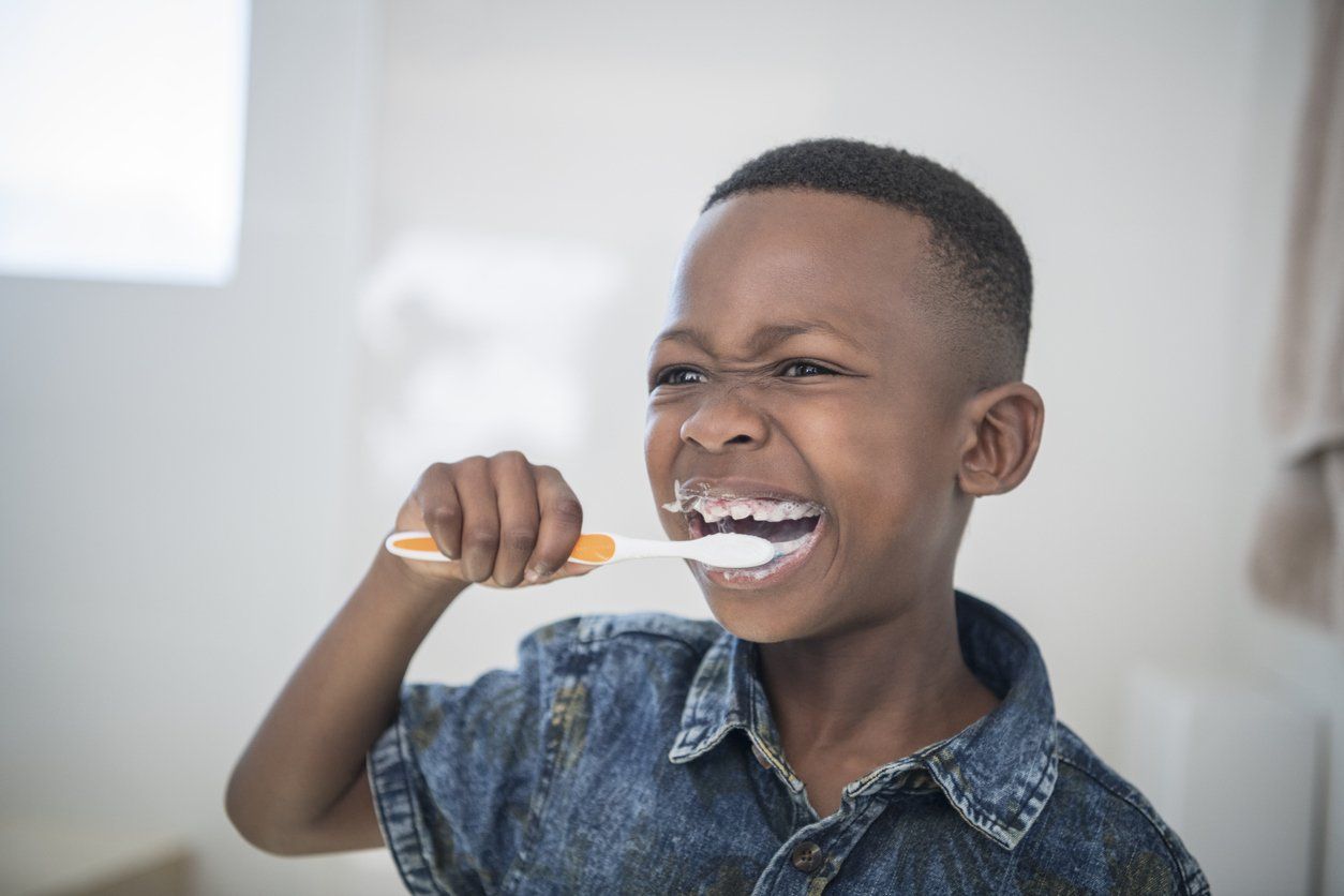 child brushing his teeth with a toothbrush