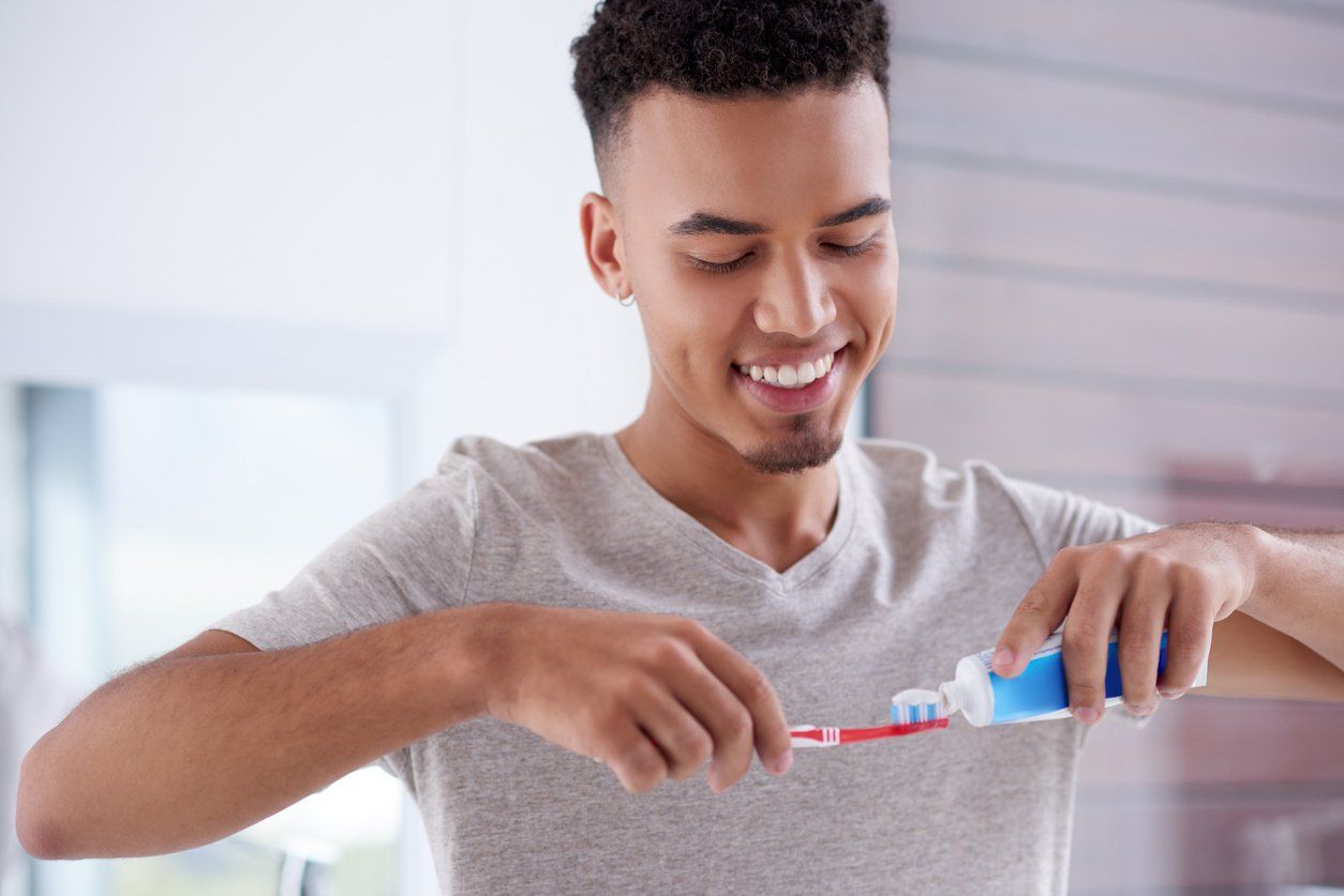 Young man about to brush his teeth to prevent halitosis.