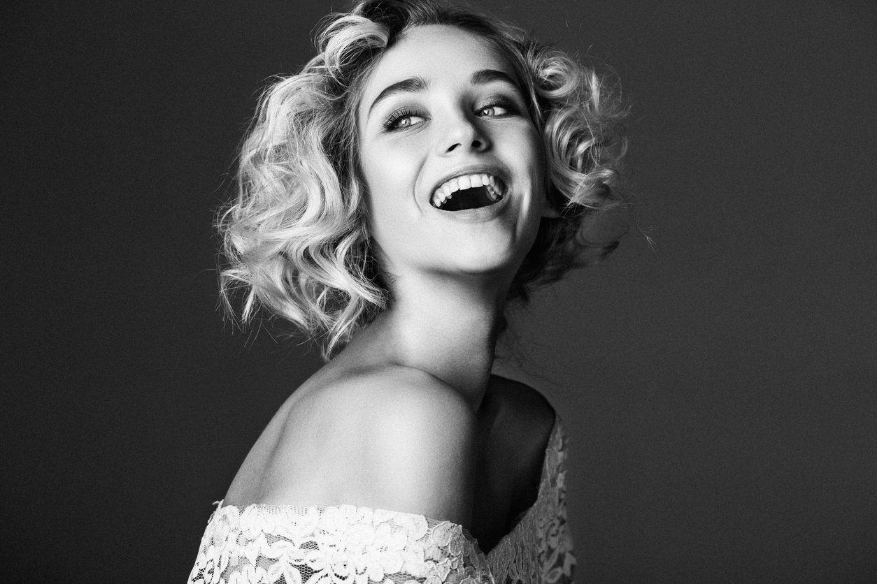 Black and white photo of woman smiling while looking off-camera.