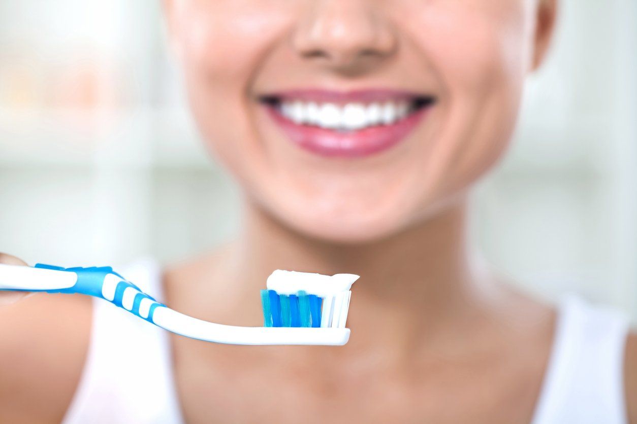 woman smiling before she uses fluoride toothpaste to brush her teeth