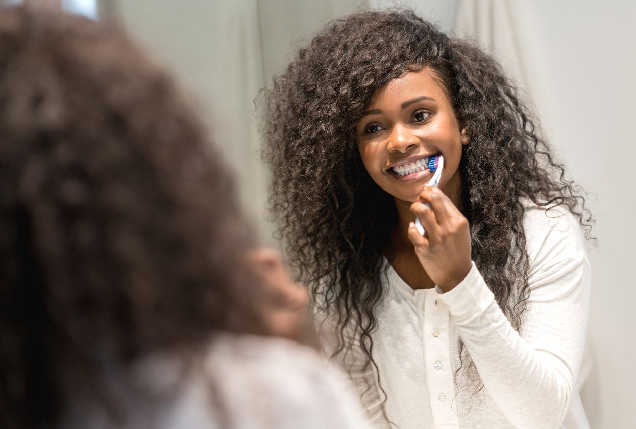 teen brushing her teeth with fluoride toothpaste to keep teeth healthy