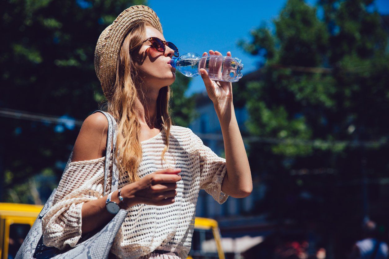 woman drinking water outdoors to combat dry mouth 