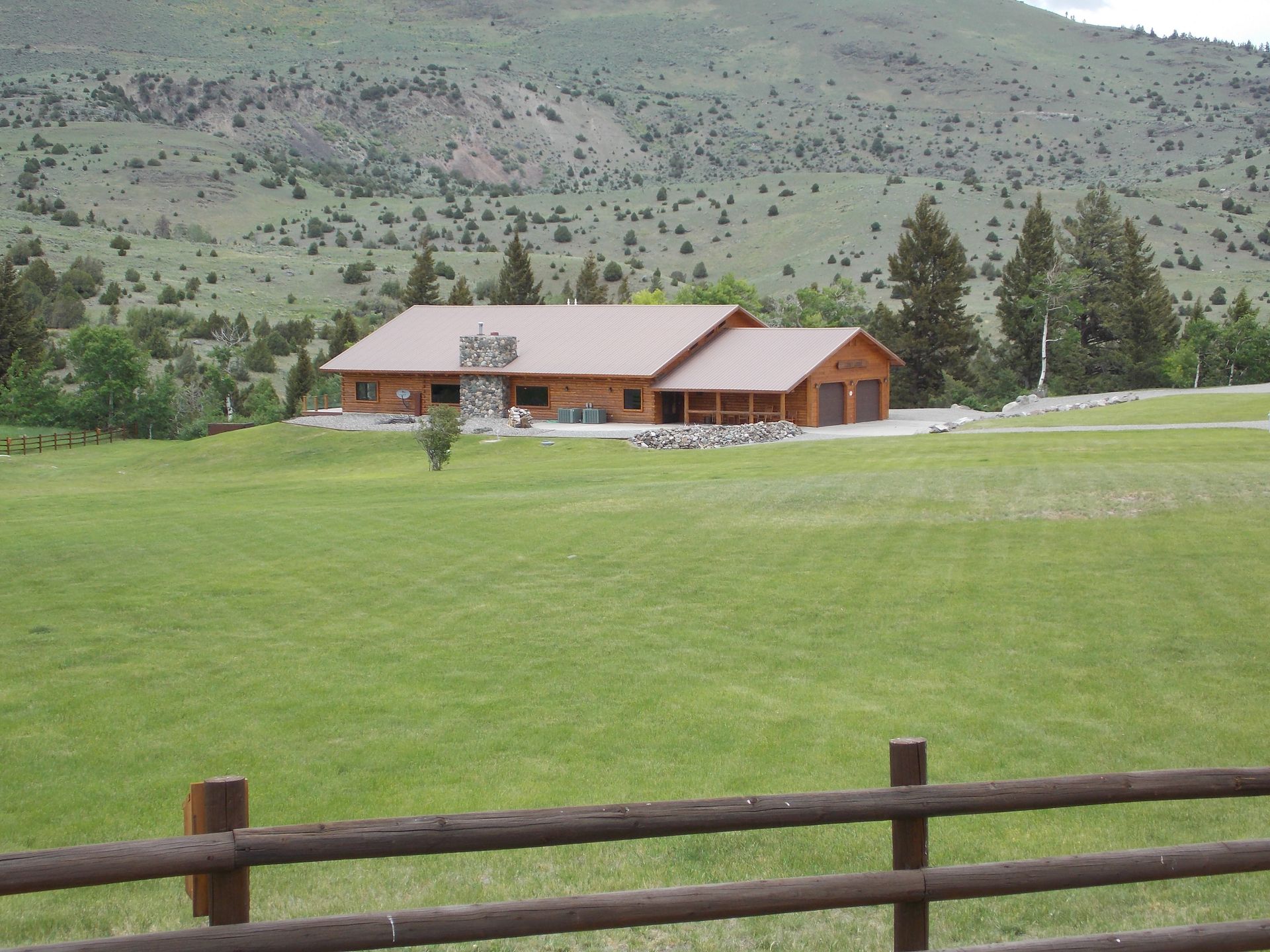 A large house sits in the middle of a grassy field