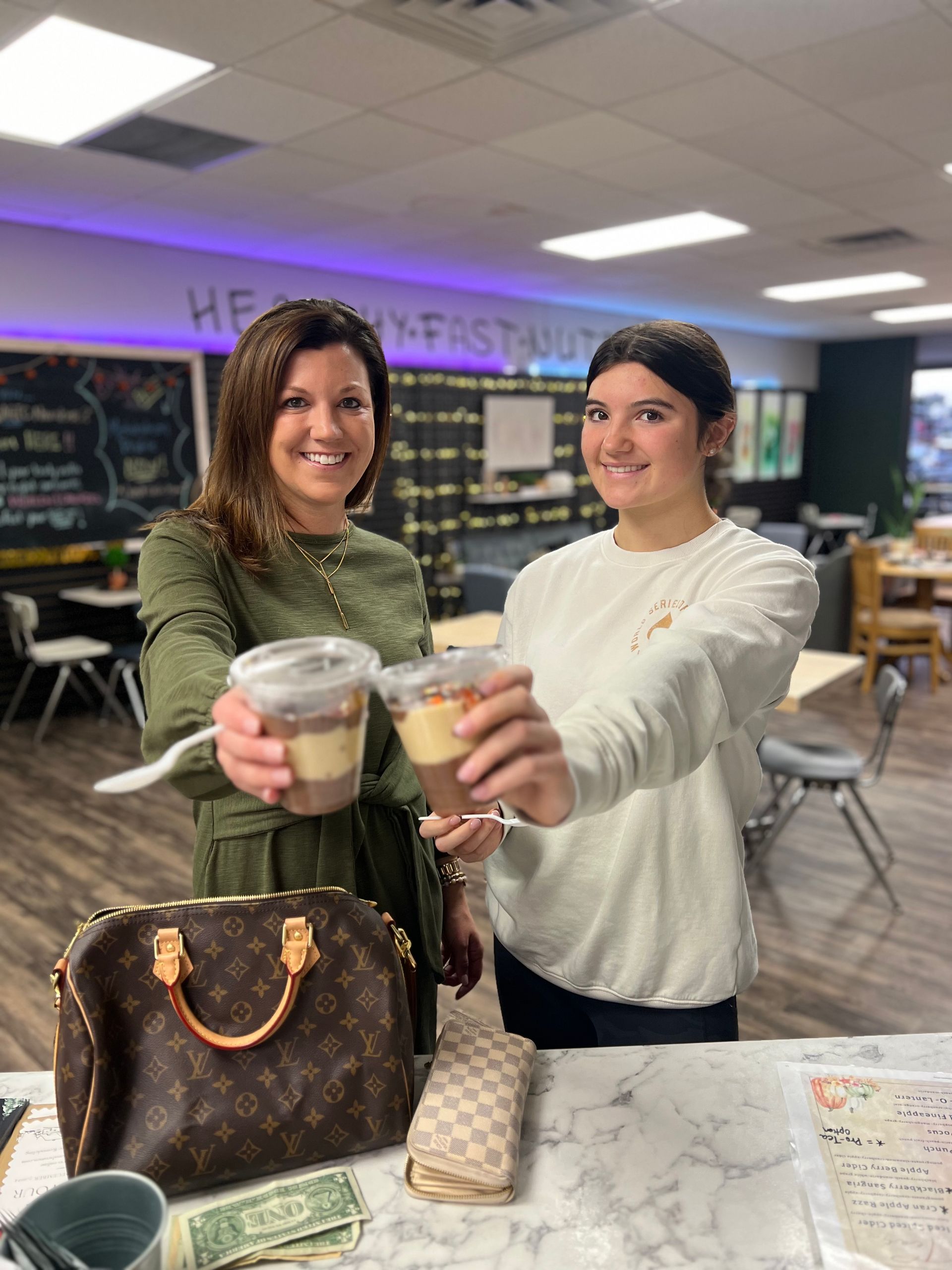 Two women are holding cups of food in their hands in a restaurant.