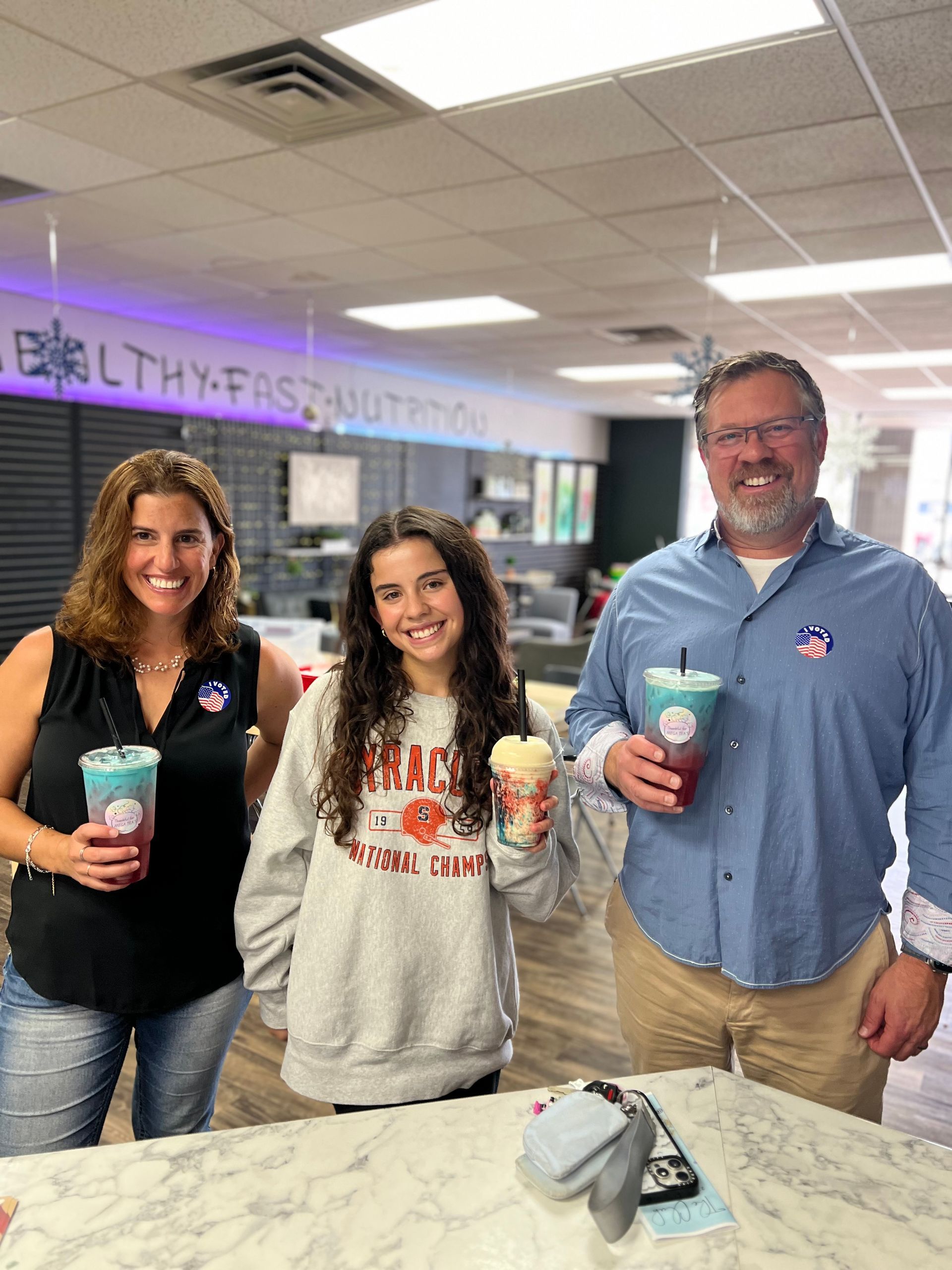 A group of people are standing next to each other in a room holding drinks.