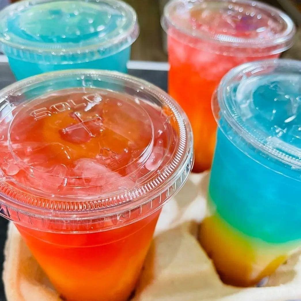 Four cups of different colored drinks are sitting on a table.