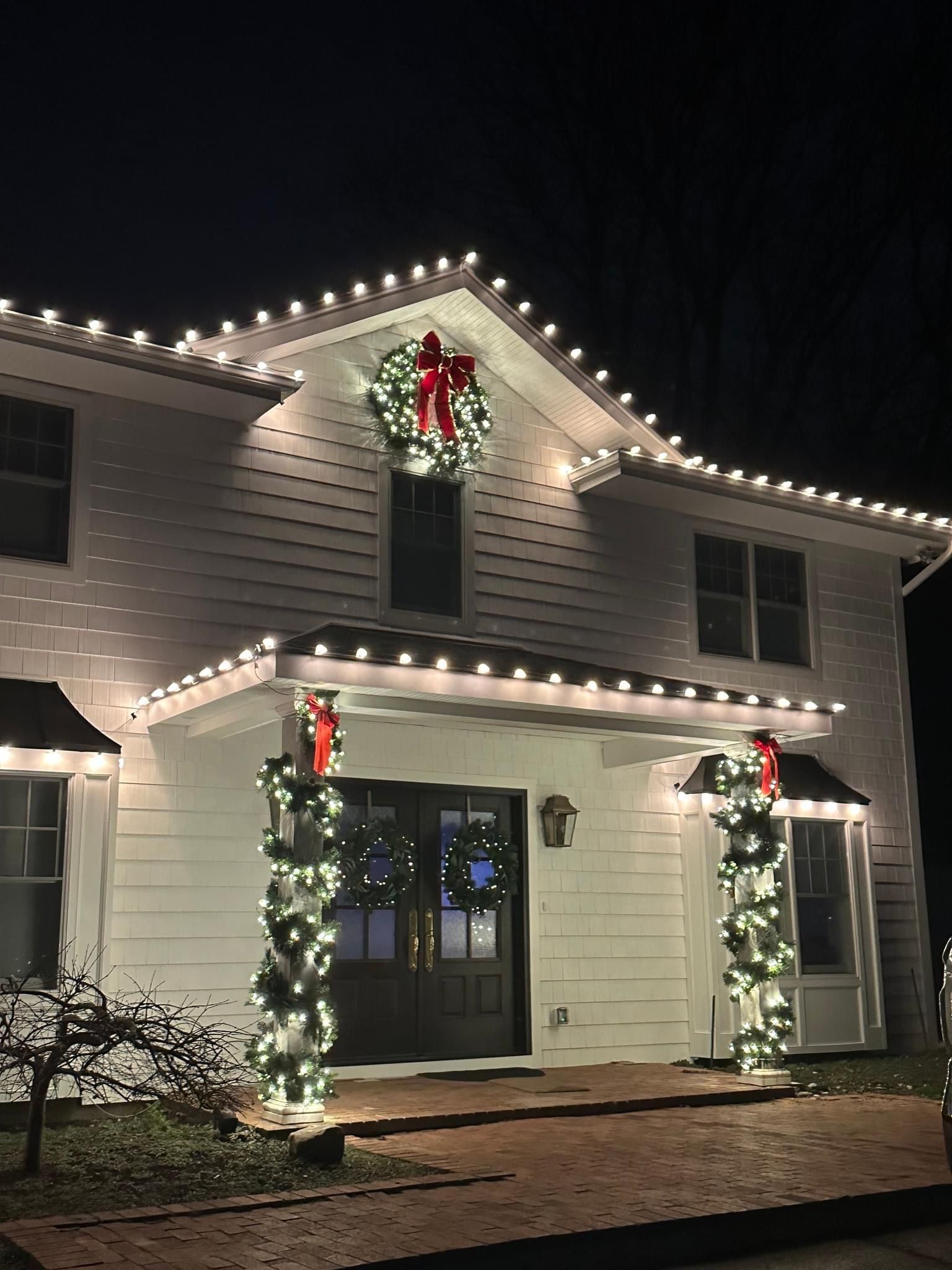 Front view of a house decorated with bright, colorful Christmas lights and holiday decorations.