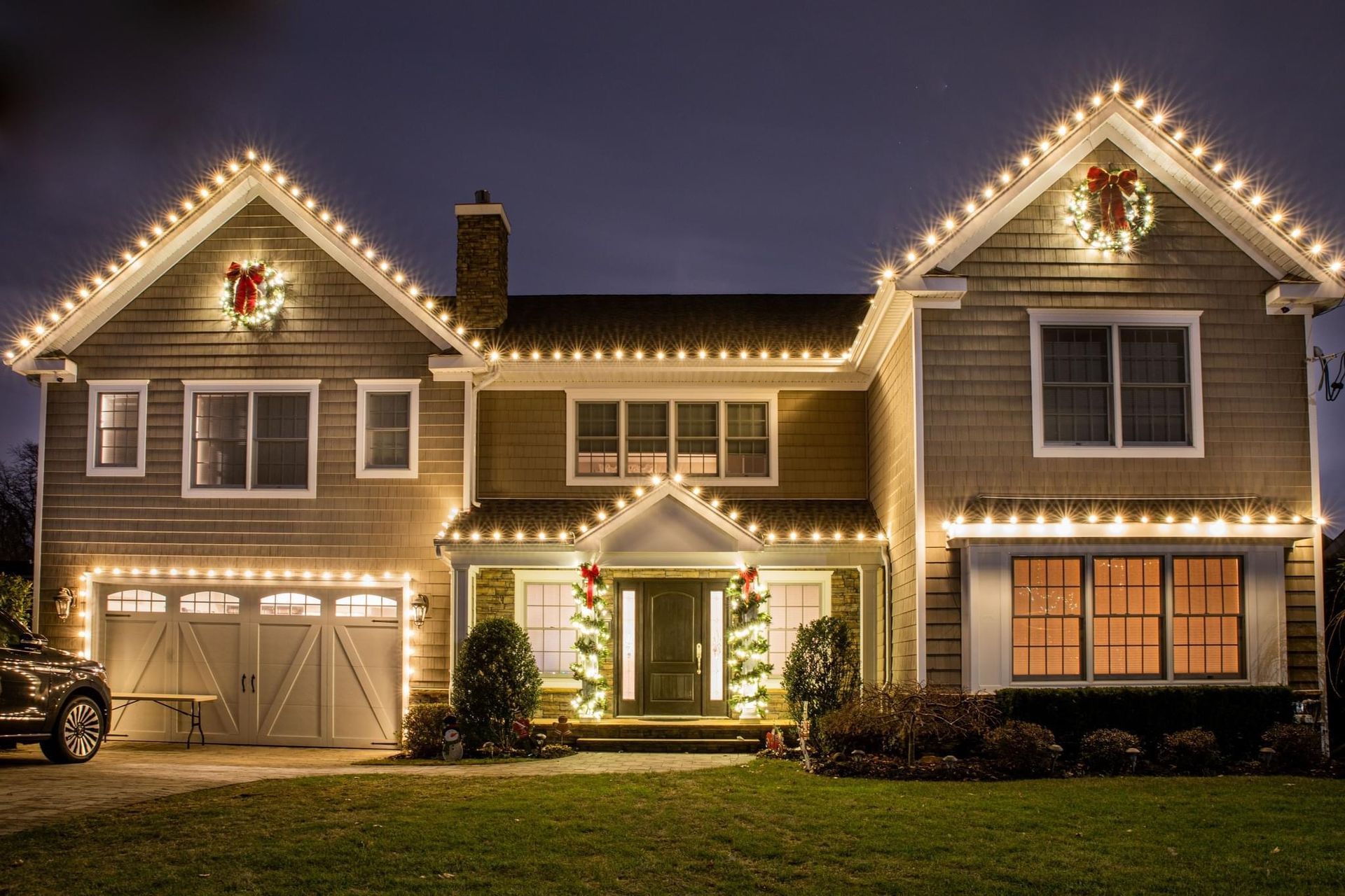 Front view of a house decorated with bright, colorful Christmas lights and holiday decorations.
