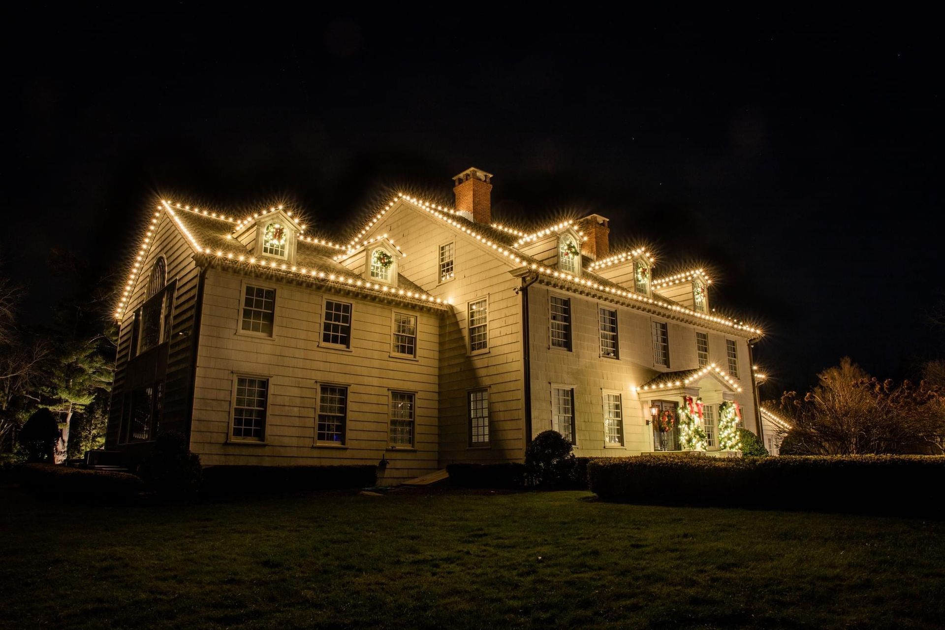 Front view of a house decorated with bright, colorful Christmas lights and holiday decorations.