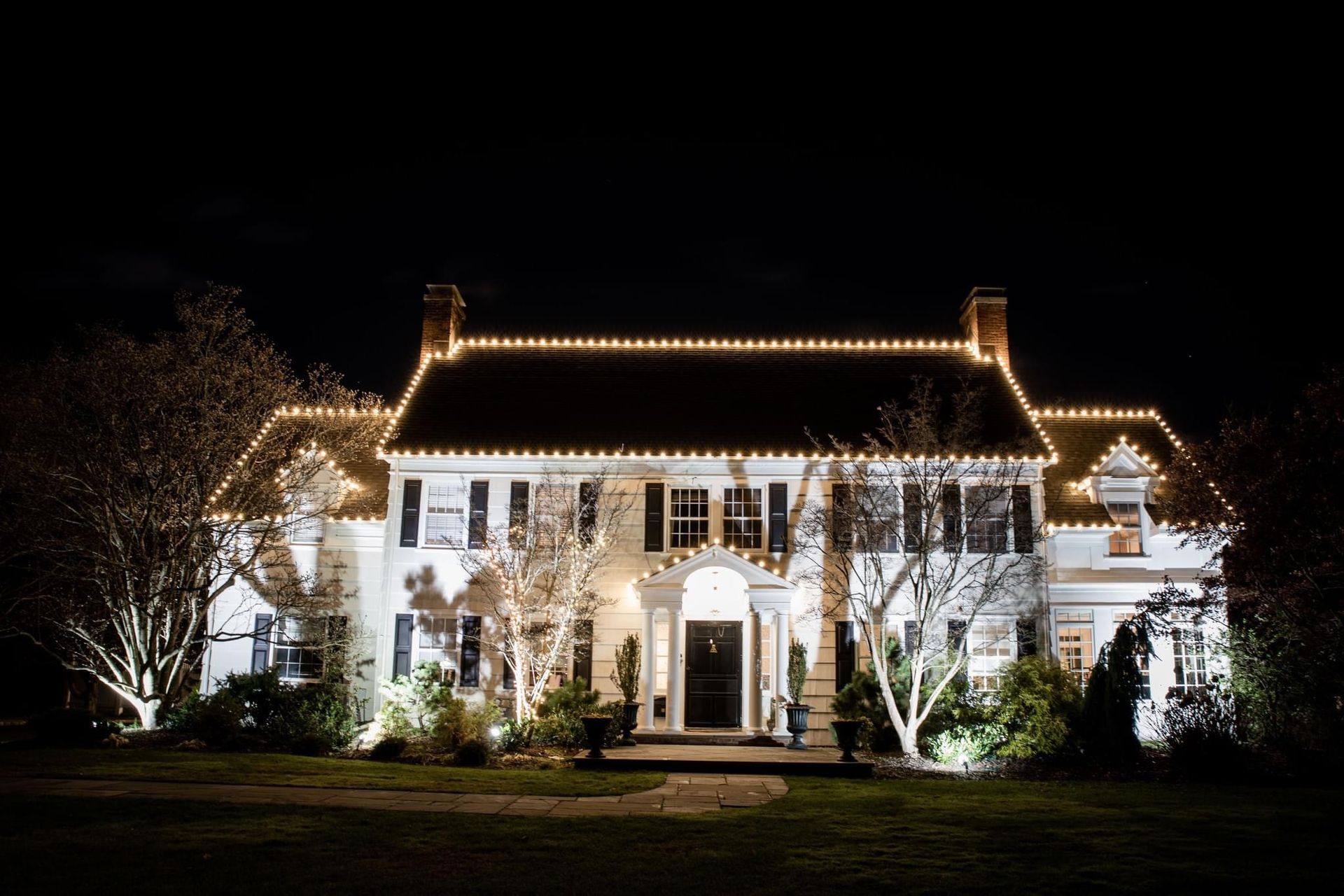 Front view of a house decorated with bright, colorful Christmas lights and holiday decorations.