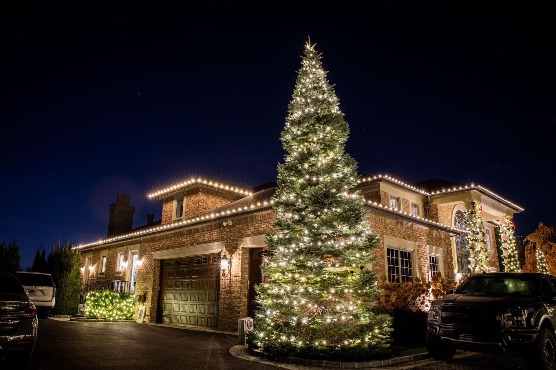Front view of a house decorated with bright, colorful Christmas lights and holiday decorations.