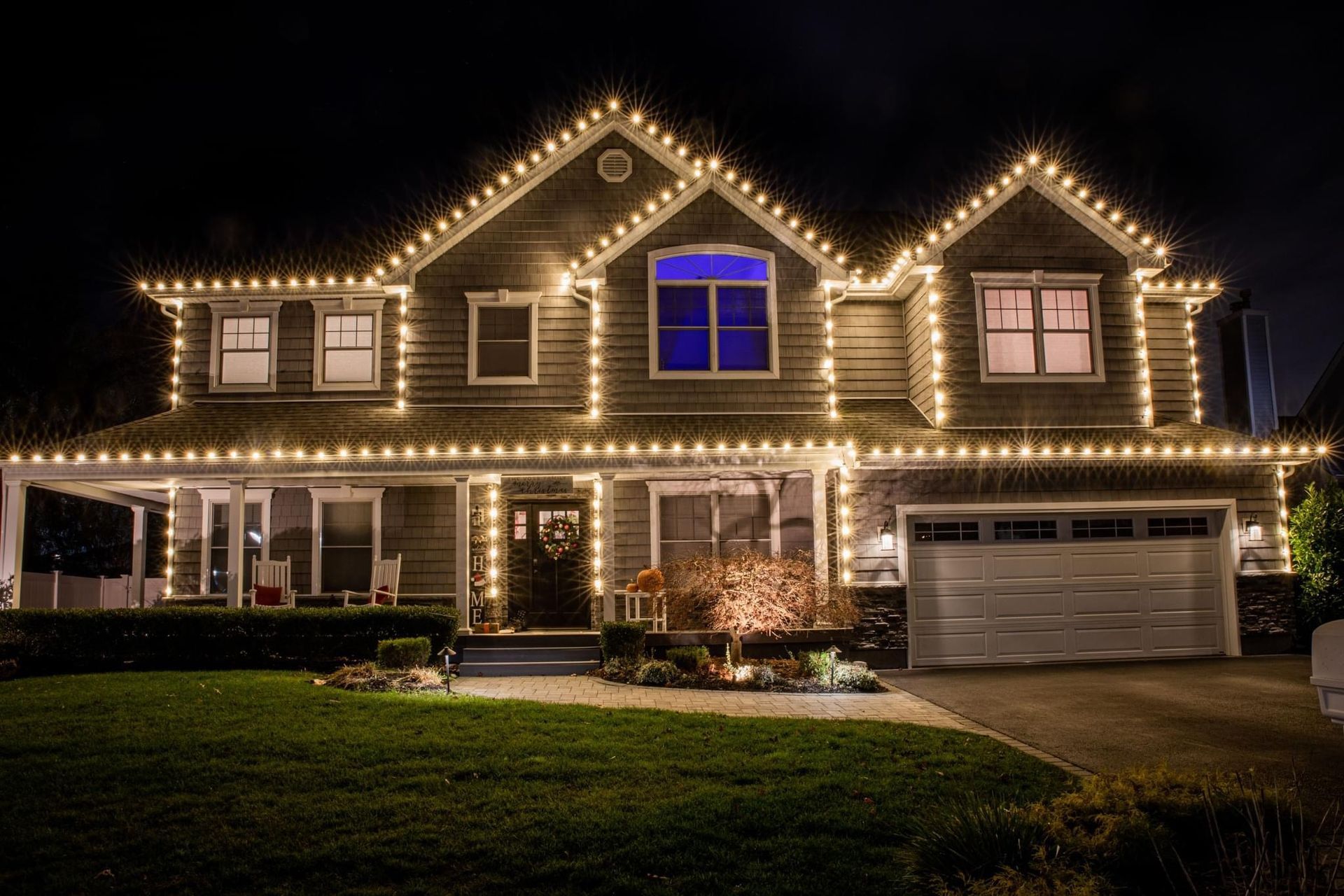 Front view of a house decorated with bright, colorful Christmas lights and holiday decorations.
