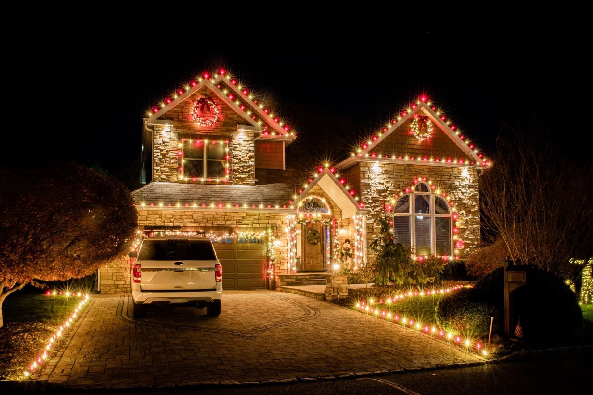 Front view of a house decorated with bright, colorful Christmas lights and holiday decorations.