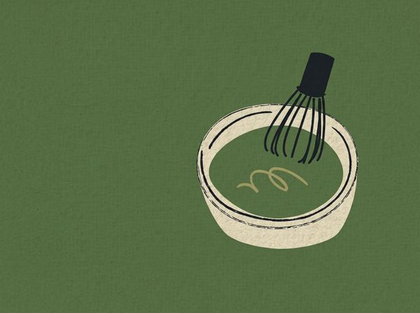 Whisk stirring green batter in a white bowl on a green background