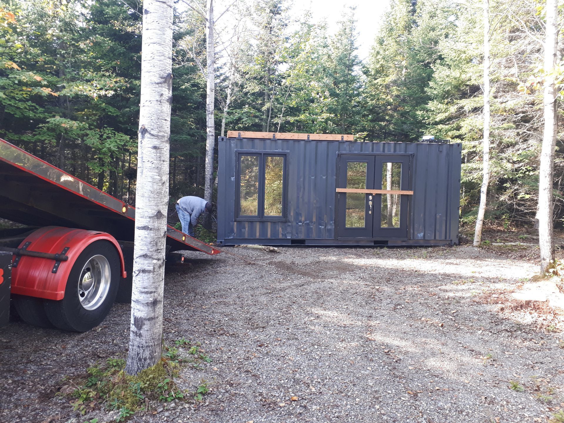 Parquet clair récemment installé dans une pièce avec une fenêtre, des murs non finis et un pied de biche rouge.