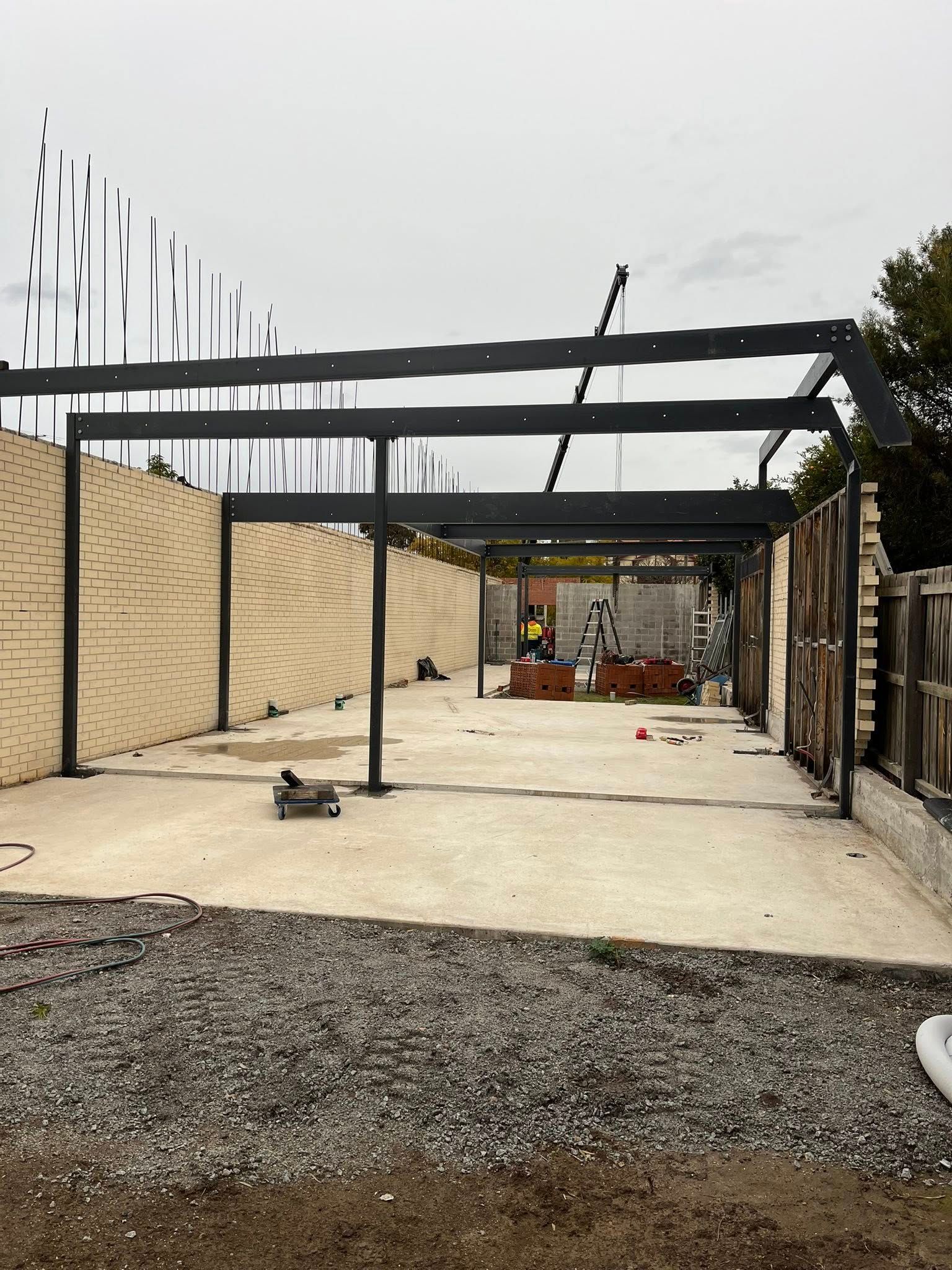 Steel framework of a building under construction, with brick walls and concrete floor.