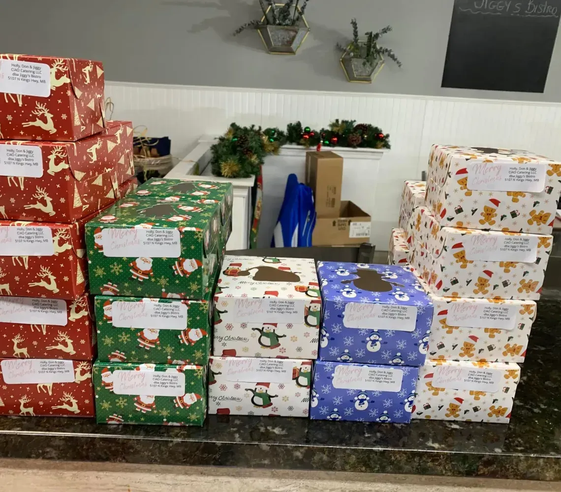 A collection of neatly wrapped Christmas gifts with handwritten address labels sitting on a dark countertop.