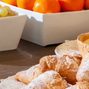 A breakfast buffet featuring bowls of fruit, pastries, brownies, and tarts arranged on a table.
