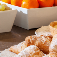 A breakfast buffet featuring bowls of fruit, pastries, brownies, and tarts arranged on a table.