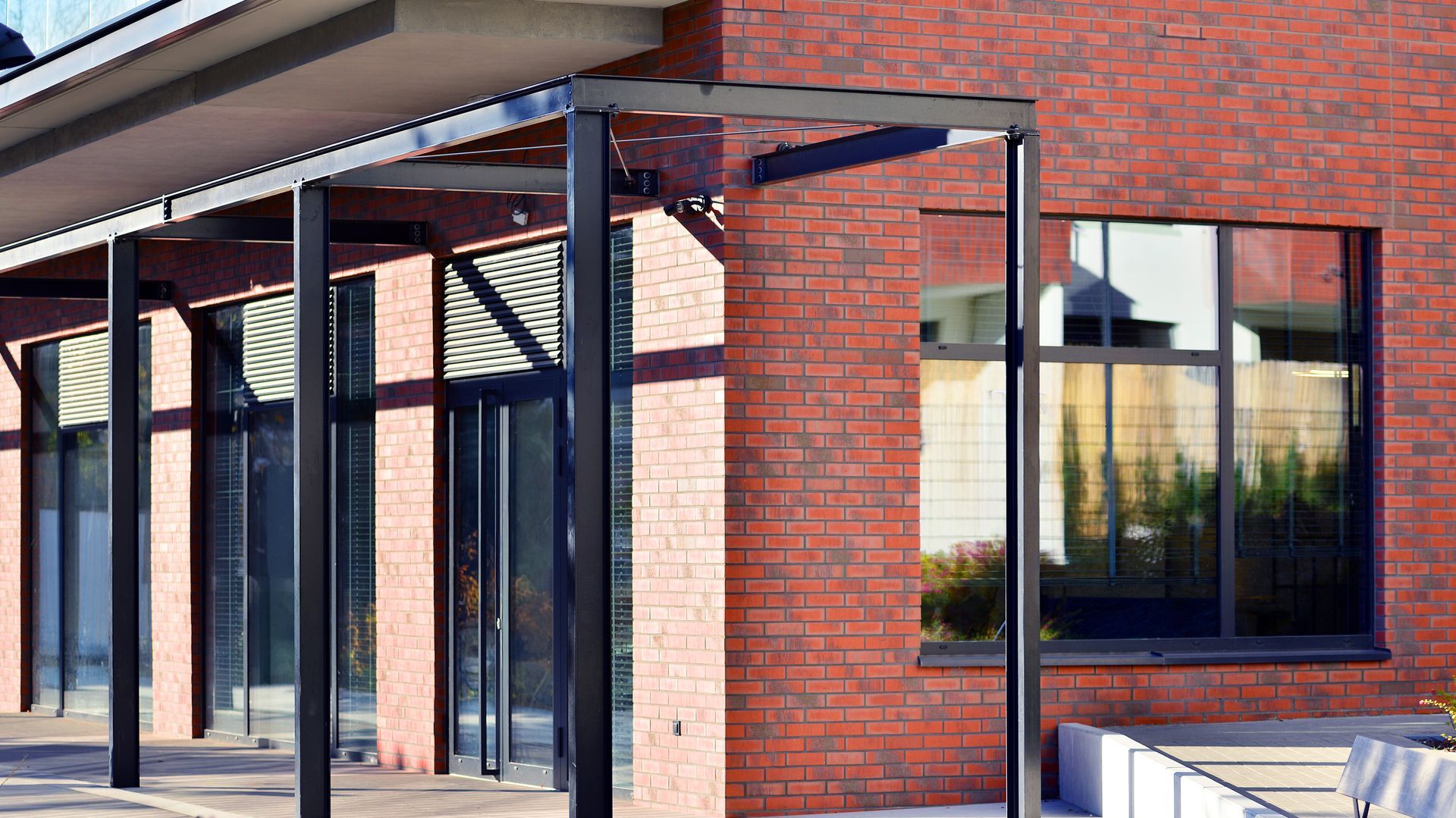Commercial building entrance with brick walls, metal canopy supports, and glass windows.