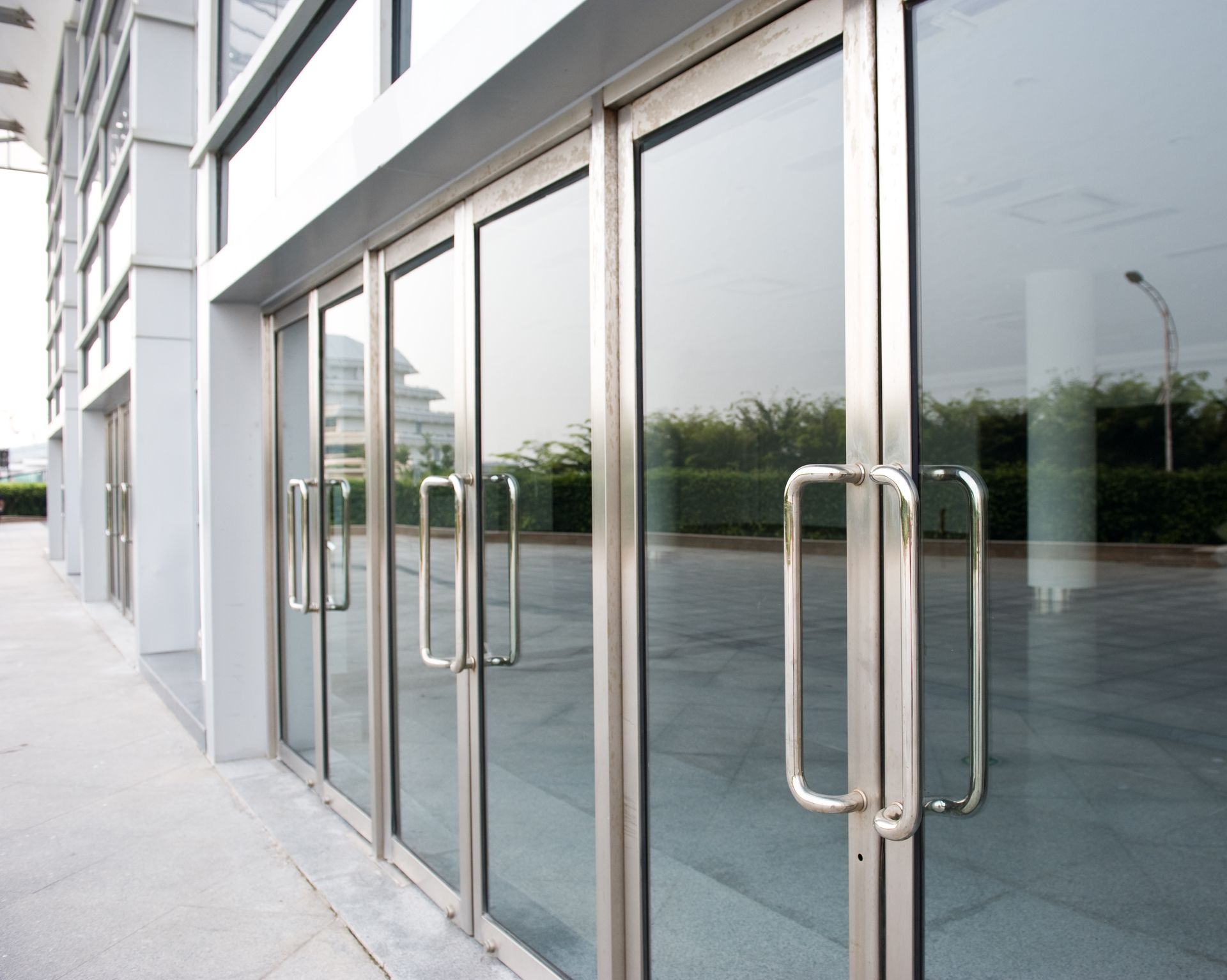 Exterior view of glass entry doors with stainless steel handles on a modern building.