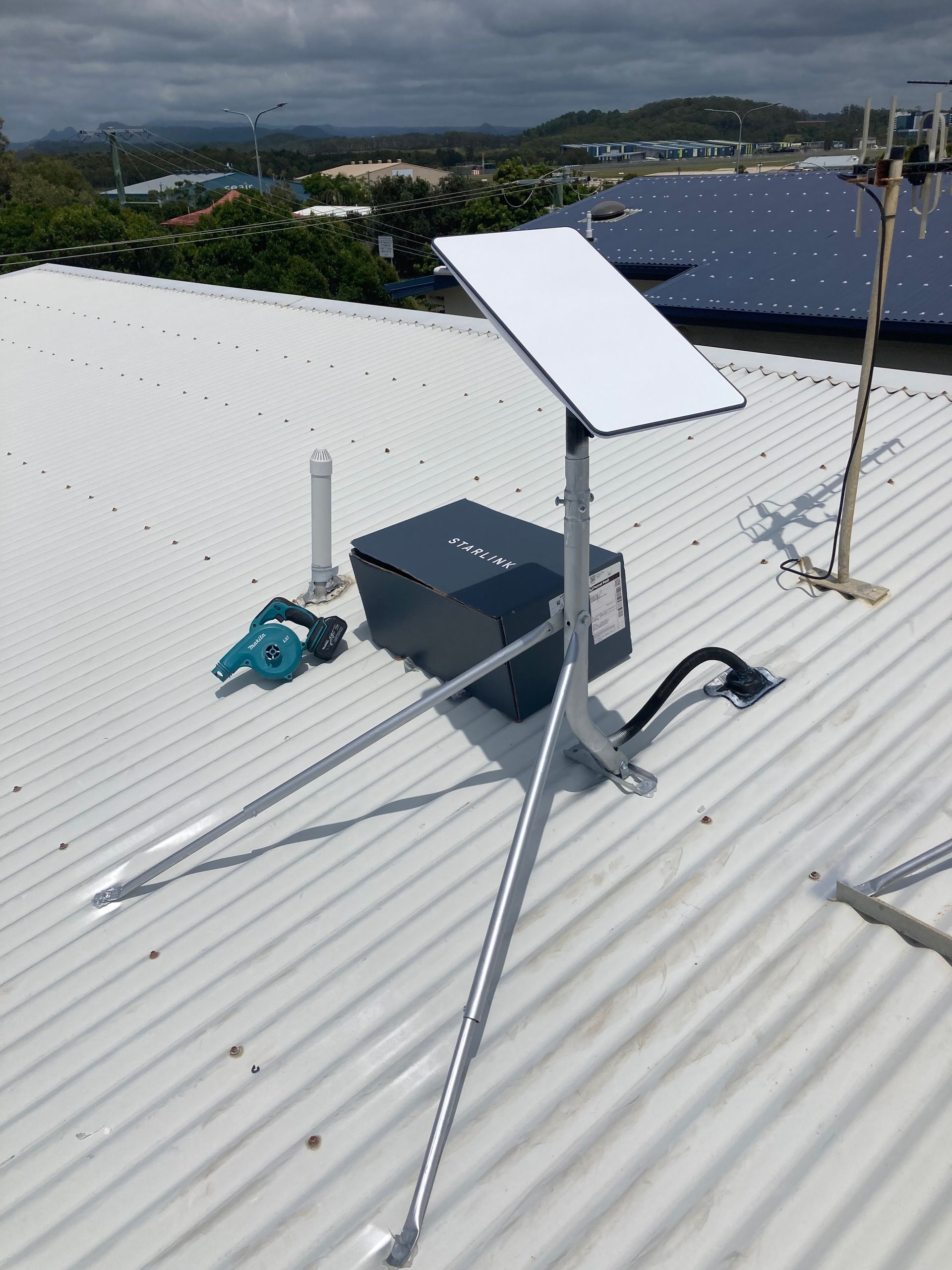 Starlink Internet Dish on a Tripod, a Black Box, and a Drill Sit on a Rooftop — BRC Antenna Service 1 In Kingscliff, NSW