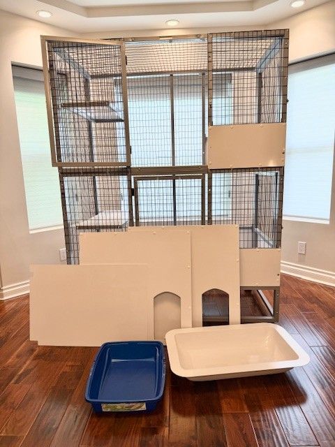 A disassembled multi-level cat enclosure with a litter box and accessories.