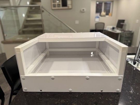 White rectangular enclosure with clear plastic sides on a countertop, interior visible.