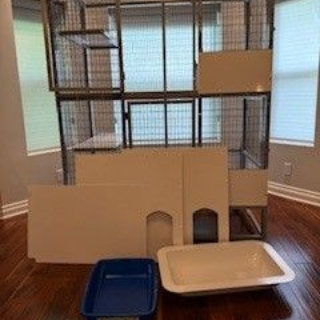 A disassembled multi-level cat enclosure with a litter box and accessories.
