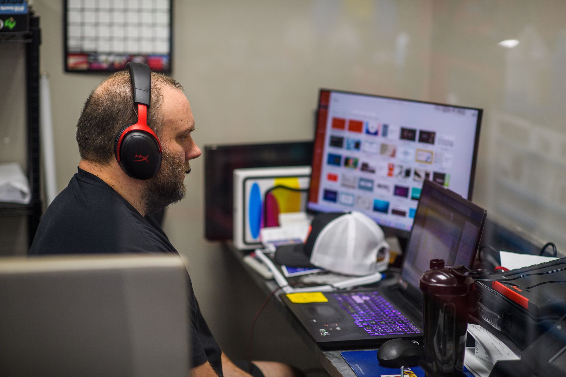 Man wearing headphones working on computer in office setting.