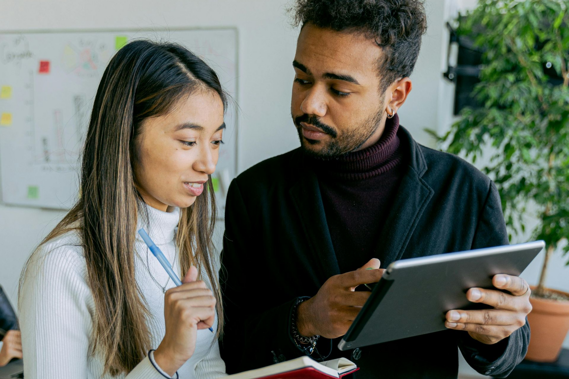 Woman and man looking at a tablet, discussing in an office setting.