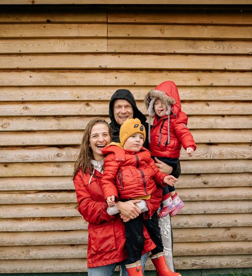 A family is posing for a picture in front of a wooden wall.