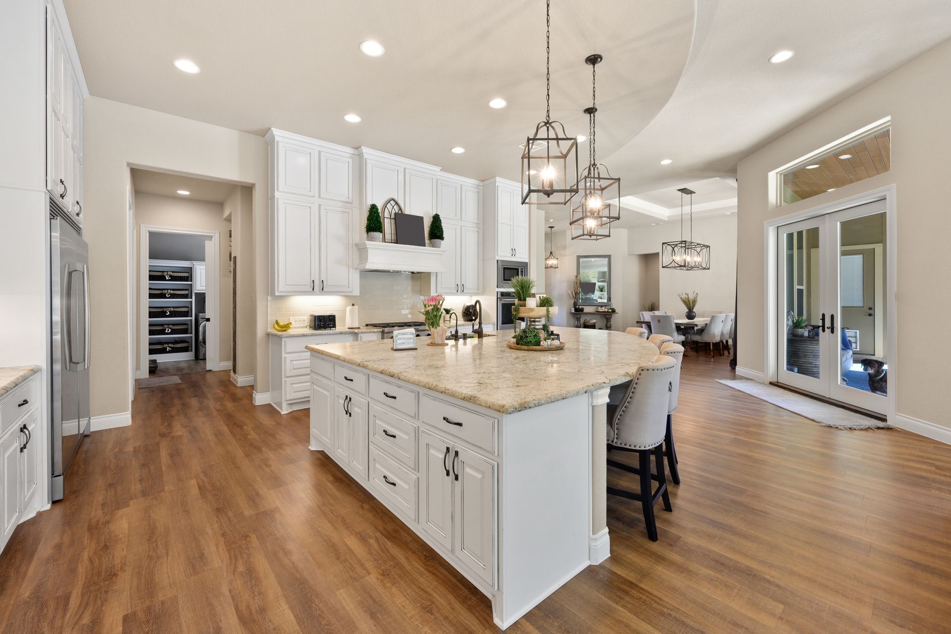Bright modern kitchen with white cabinets, large island, pendant lights, and hardwood floors