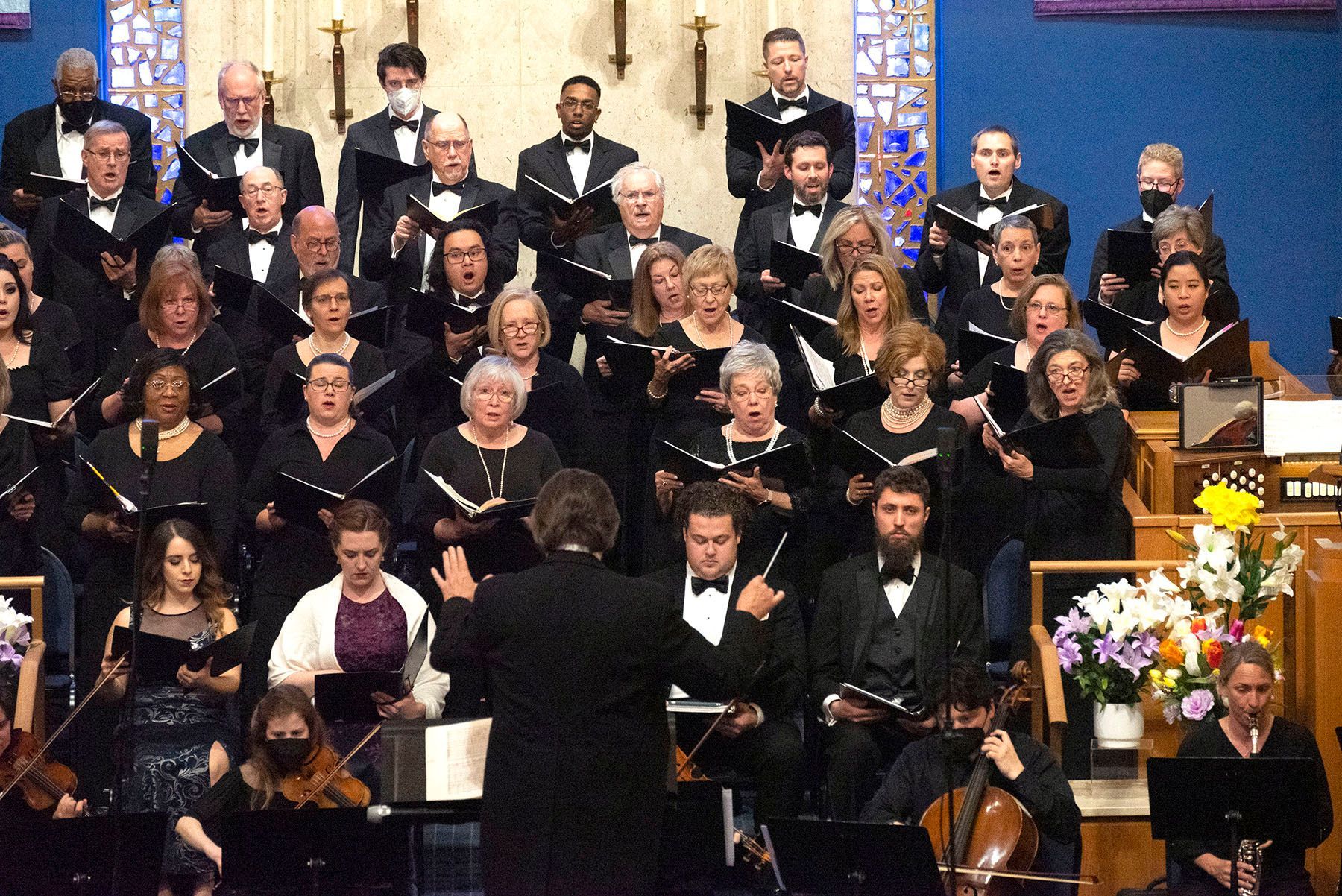 a large choir singing in a church with a conductor