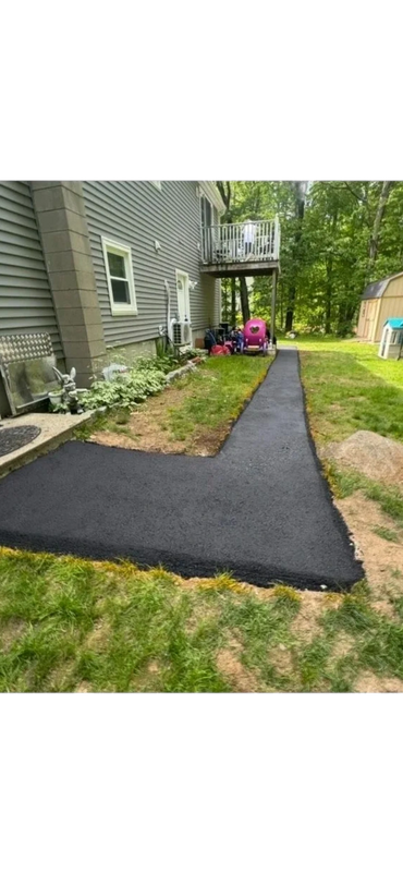Asphalt path extending from a house to the backyard.